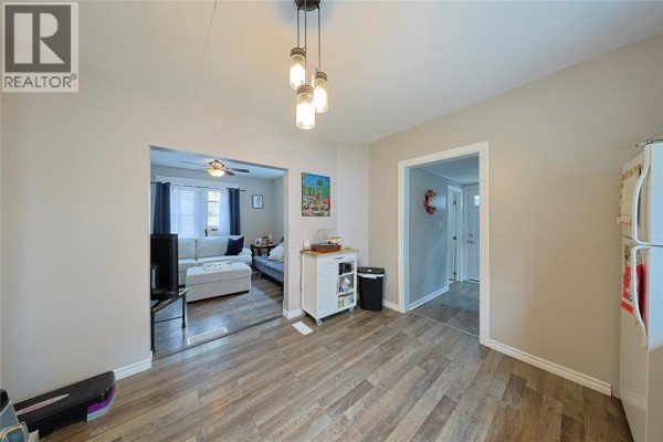 View from kitchen showing living room and hallway, with wood-look flooring. - 414 Davis Street, Sarnia