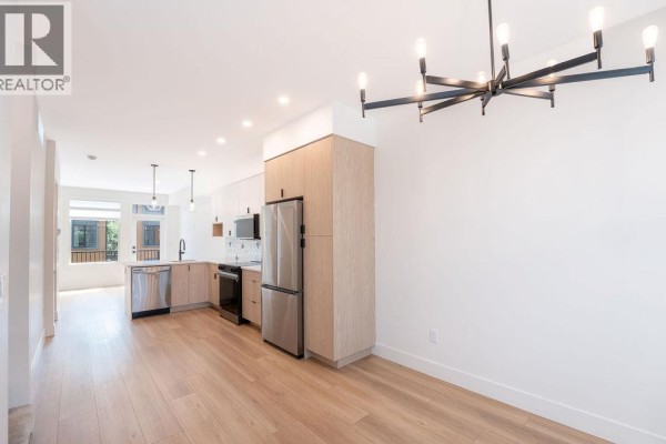 Open concept living area with kitchen, stainless steel appliances and wood floors. - 414 Humbert Street Unit# 4, Revelstoke
