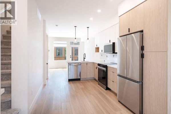Kitchen area with light wood cabinets, stainless steel appliances, and island. - 414 Humbert Street Unit# 4, Revelstoke