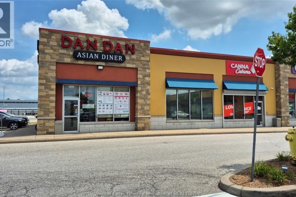Seating area with red booths and tables next to a food preparation counter with digital menu boards. - 4140 Walker Road Unit# 200-101, Windsor