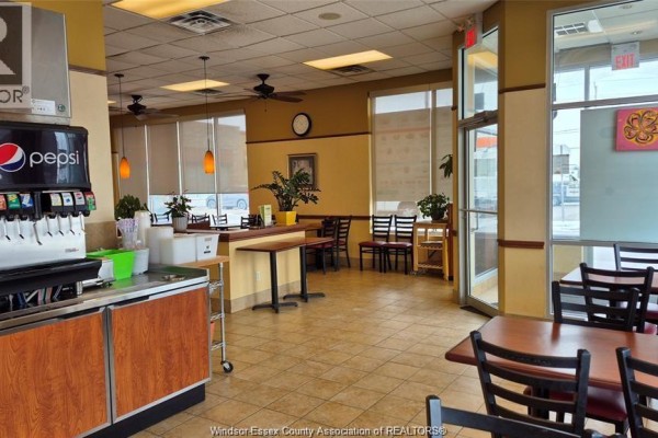 View of tables and chairs near large windows with blinds and a view of the street. - 4140 Walker Road Unit# 200-101, Windsor