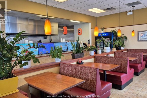 Commercial kitchen with stainless steel equipment, ventilation hood, and cooking stations. - 4140 Walker Road Unit# 200-101, Windsor