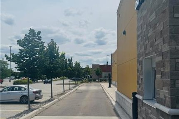 Exterior view of a commercial building with a drive-thru lane and parking lot. - 4140 Walker Road, Windsor
