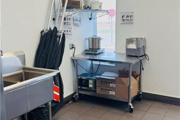 Commercial kitchen area with a stainless steel sink, counter, and appliances. - 4140 Walker Road, Windsor
