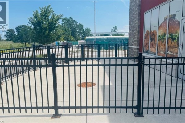 Black metal fence in front of a commercial building with a graphic advertisement. - 4140 Walker Road, Windsor