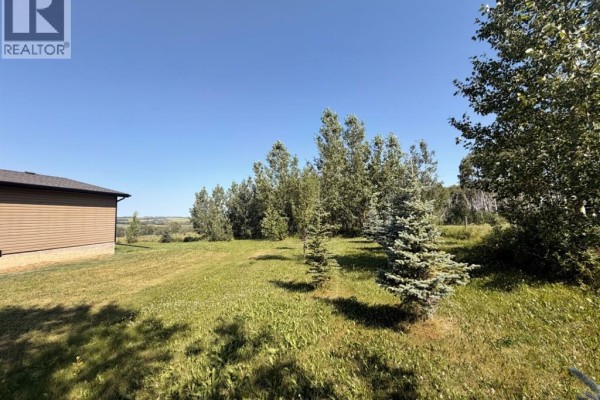 Back view of a brown house with double doors, windows, and a satellite dish. - 4142 Township Road 290, Rural Mountain View County