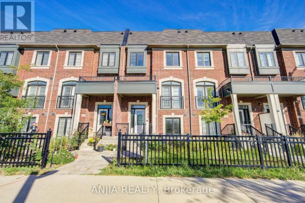 Exterior view of a red brick townhouse with black trim and balconies under a blue sky. - 4146 Highway 7 Road E, Markham