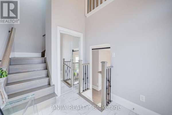 Interior staircase with light wood steps and railings, leading to a second floor with a mirrored closet. - 4146 Highway 7 Road E, Markham