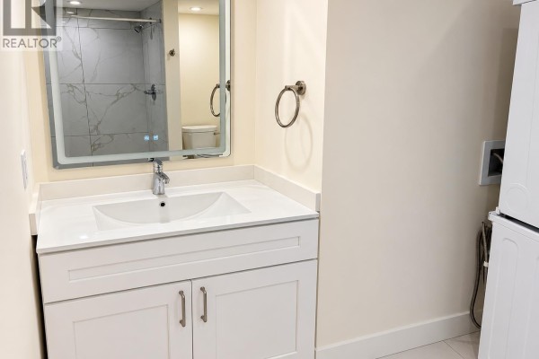 Bathroom with a white vanity, modern sink, LED mirror, and tiled shower. - 4147 W13th Ave, Vancouver
