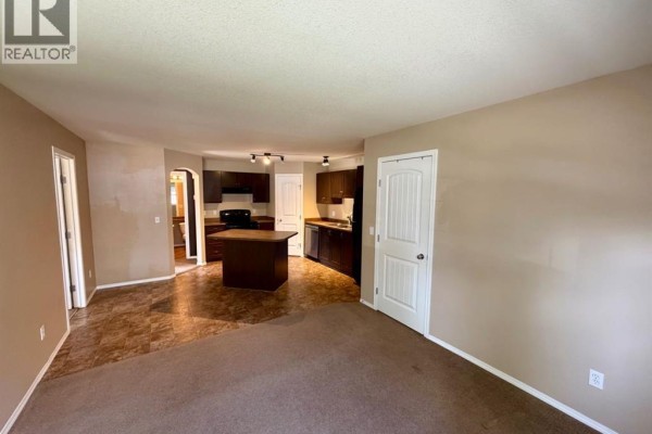 Open concept living area and kitchen with dark wood cabinets and island. - 415, 31 Jamieson Avenue, Red Deer