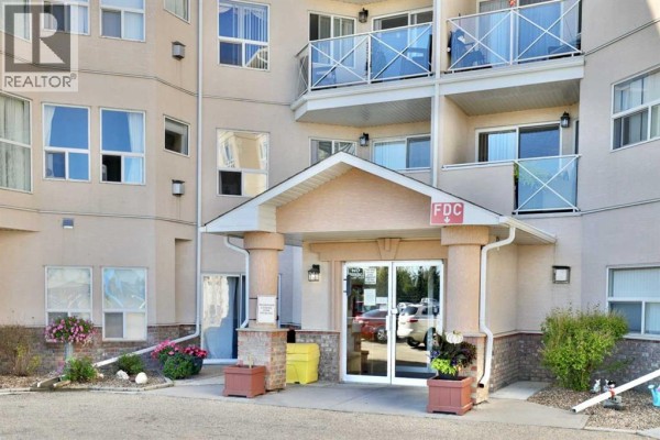 Front exterior of a beige, multi-story apartment building with balconies and large windows. - 415, 4623 65 Street, Camrose
