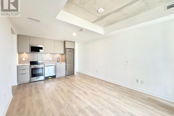 Living area with light wood flooring and a modern grey kitchen unit. - 415 - 1 Vine Avenue, Toronto