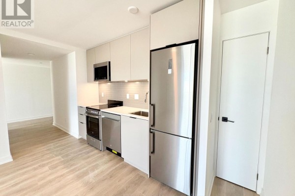 Kitchen area with stainless steel refrigerator, oven, and light grey cabinets. - 415 - 1 Vine Avenue, Toronto