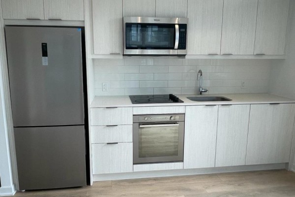 Compact kitchen featuring stainless steel appliances, white cabinetry, and a tiled backsplash - 415 - 38 Forest Manor Road, Toronto