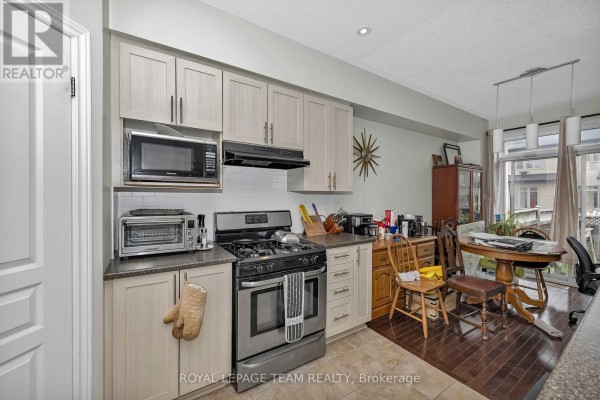 Kitchen with light wood cabinets, stainless steel appliances, and a dining area. - 415 Arncliffe Avenue, Ottawa