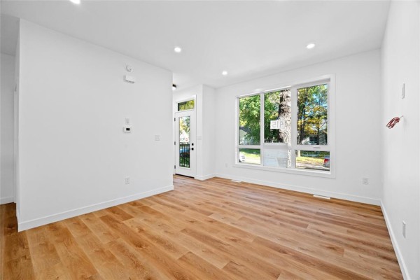 Living room with white walls, blonde wood laminate flooring, recessed lighting, and a large window. - 415 Centennial Street, Winnipeg