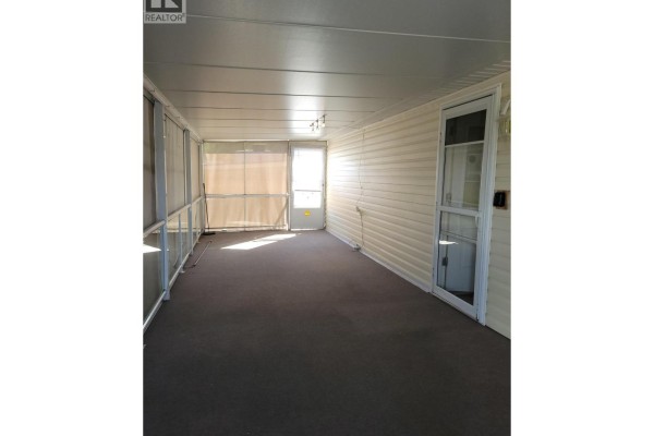 Interior view of a carpeted sunroom with beige siding, lighting fixtures, and screened windows. - 415 Commonwealth Road Unit# 298, Lake Country