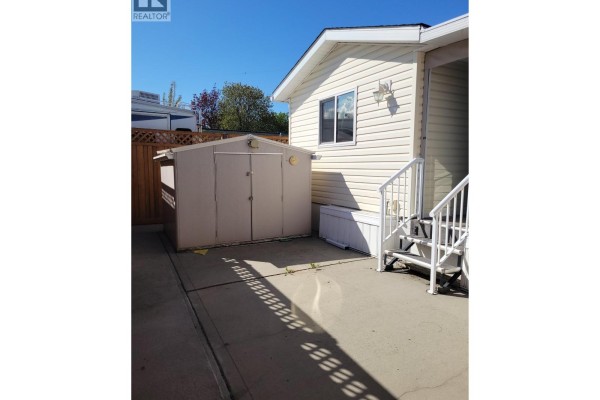 Backyard area with a tan storage shed, outdoor steps, and a wooden fence. - 415 Commonwealth Road Unit# 298, Lake Country