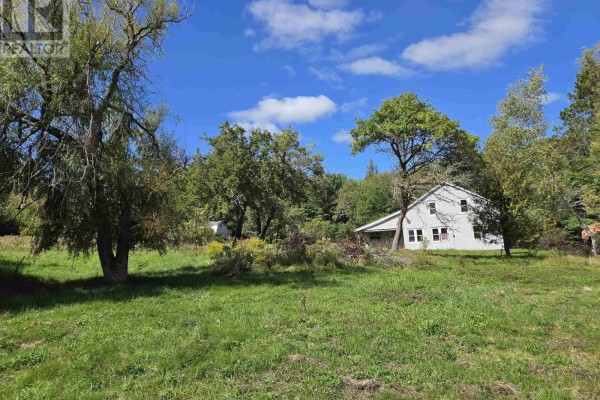 Side view of a light blue house surrounded by green trees and a large grassy area. - 415 Old Harmony Road, Harmony Mills