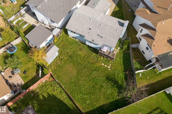 Aerial view of a backyard with green grass, wooden deck, and shed. - 4151 28 Av Nw, Edmonton