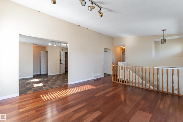 Interior view of a living room with hardwood floors and open doorways to other rooms. - 4151 28 Av Nw, Edmonton