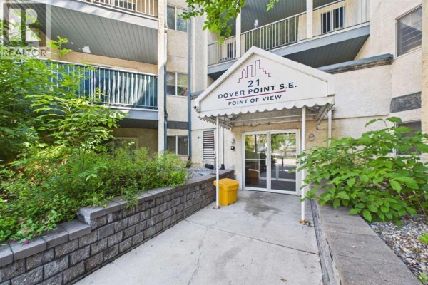 Close-up of the apartment building entrance with glass doors and a white awning. - 416, 21 Dover Point Se, Calgary