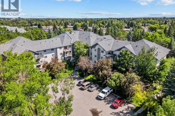 Aerial view of the apartment building surrounded by trees and a parking lot. - 416, 21 Dover Point Se, Calgary