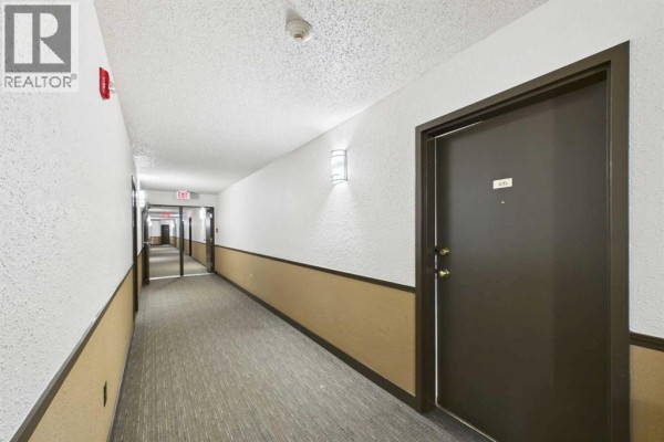 Interior apartment building hallway with doors, carpet, and wall sconces. - 416, 21 Dover Point Se, Calgary