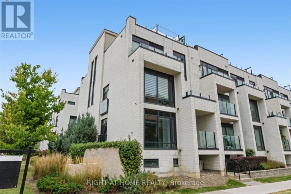Side view of a townhouse complex with trees and landscaping. - 416 - 130 Widdicombe Hill Boulevard, Toronto