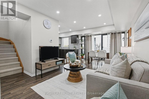 Living room with a sofa, TV, stairs, and dining area view. - 416 - 130 Widdicombe Hill Boulevard, Toronto