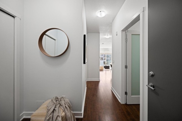 Hallway view with wood floors, white doors, and abstract art on the wall. - 416 20460 Douglas Crescent, Langley