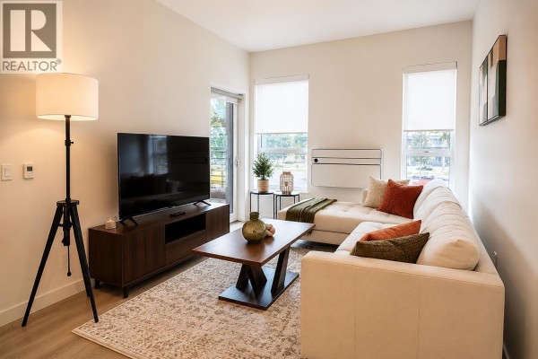 Living room featuring a sectional sofa, coffee table, television, and floor lamp. - 416 245 Bewicke Avenue, North Vancouver