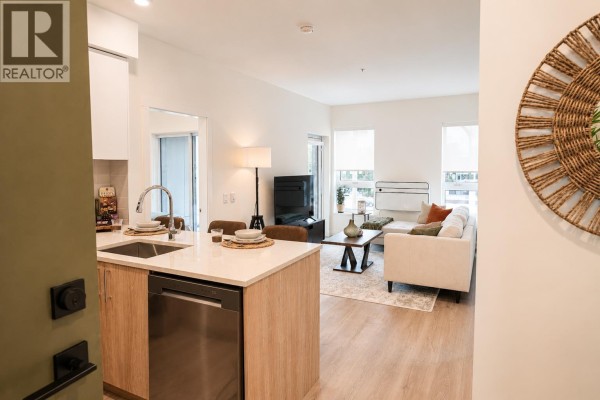 View from doorway into open-plan kitchen and living room with light wood floors. - 416 245 Bewicke Avenue, North Vancouver