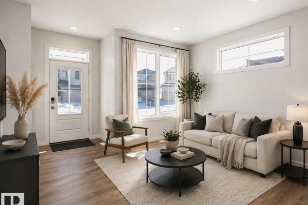 Living room with beige sofa, armchair, coffee table, and large windows. - 416 26 St Sw, Edmonton