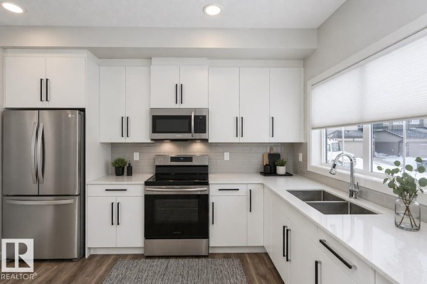 Modern kitchen with white cabinets, stainless steel appliances, and quartz countertops. - 416 26 St Sw, Edmonton