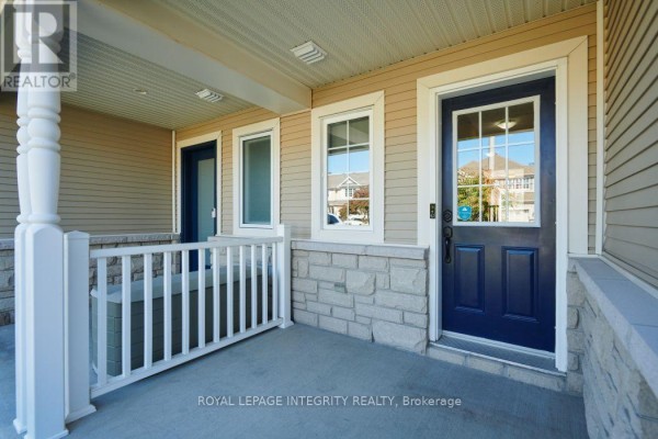 Covered front porch with beige siding, stone base, white railings, and blue front door. - 416 Wisteria Crescent, Ottawa