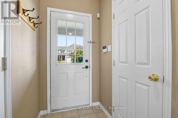 Interior view of a bright entryway with a white door, coat hooks, and tiled floor. - 416 Wisteria Crescent, Ottawa