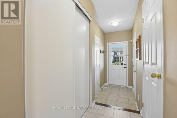 Hallway with beige walls, tiled floor, a large closet, and a view of the front door. - 416 Wisteria Crescent, Ottawa