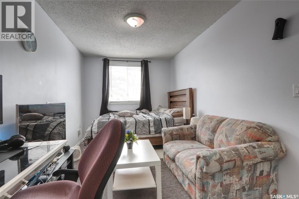 Living room with dark brown leather sofas, glass coffee table, and gray carpet. - 4160 Castle Road, Regina