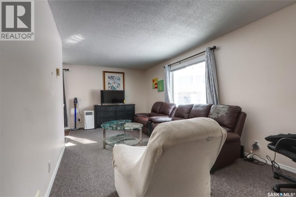 Living room with recliners, glass coffee table, and view of entryway and stairs. - 4160 Castle Road, Regina