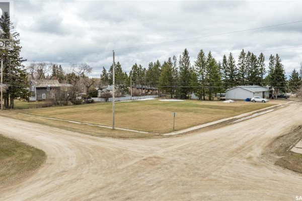 Corner lot view of the vacant land with houses and trees in the background. - 417 5th Street, Duck Lake