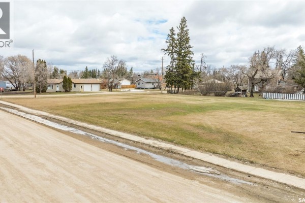 View of the empty lot with a dirt road and houses in the distance. - 417 5th Street, Duck Lake
