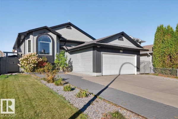 Side exterior view of a grey house with a white garage door and a paved walkway. - 417 Hollick Kenyon Rd Nw Nw, Edmonton