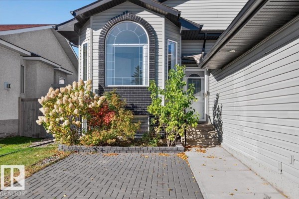 Close-up of the entrance to a grey house with a large arched window and landscaping. - 417 Hollick Kenyon Rd Nw Nw, Edmonton