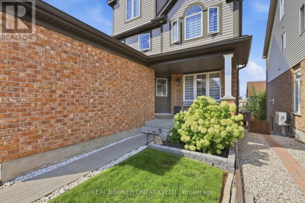 Front entrance with red brick and grey siding, porch with seating and landscaping. - 417 Jolliffe Avenue, Guelph/eramosa