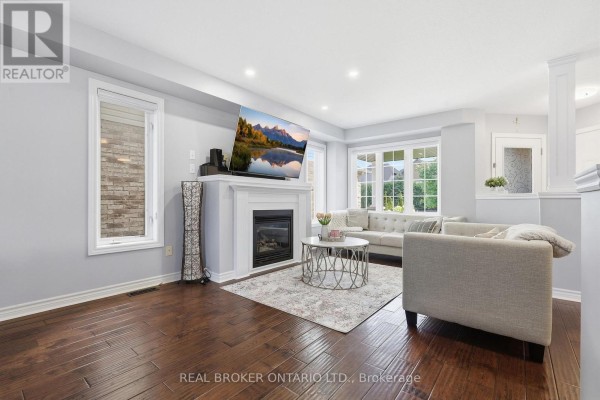 Living room with a fireplace, grey sofas, coffee table, and dark hardwood floors. - 417 Jolliffe Avenue, Guelph/eramosa
