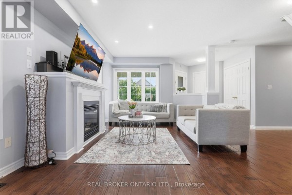 Living room with a fireplace, tufted sofas, coffee table, and dark hardwood floors. - 417 Jolliffe Avenue, Guelph/eramosa