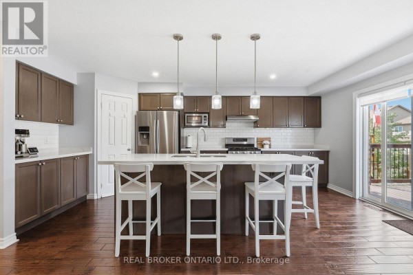 Kitchen with dark cabinets, white countertops, a large island with bar stools, and stainless steel appliances. - 417 Jolliffe Avenue, Guelph/eramosa