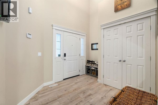 View from the foyer looking towards the front entrance and staircase, with a bathroom doorway on the left. - 417 River Heights Drive, Cochrane