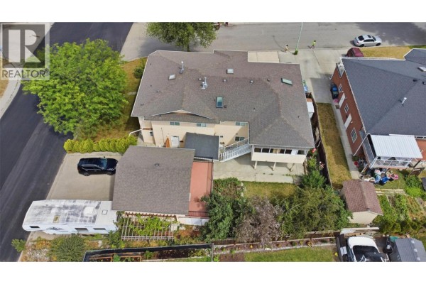 Aerial view of the property's backyard with a detached garage, RV parking, and mature trees. - 417 Wigglesworth Crescent, Kelowna